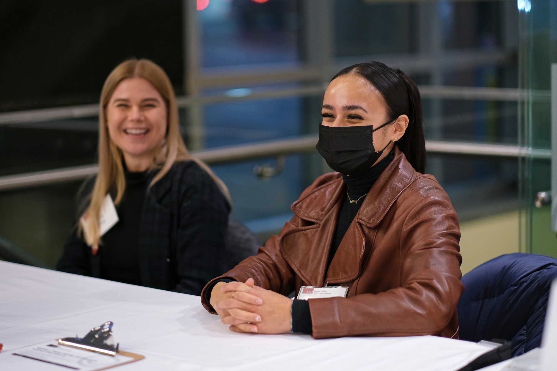 Marihah Hussainaly Farouk smiling in a mask at her work event for the Centre for Dialogue. On her left is her colleague, Karis Chitty.