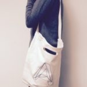 A person modelling a tote bag with the "A" logi