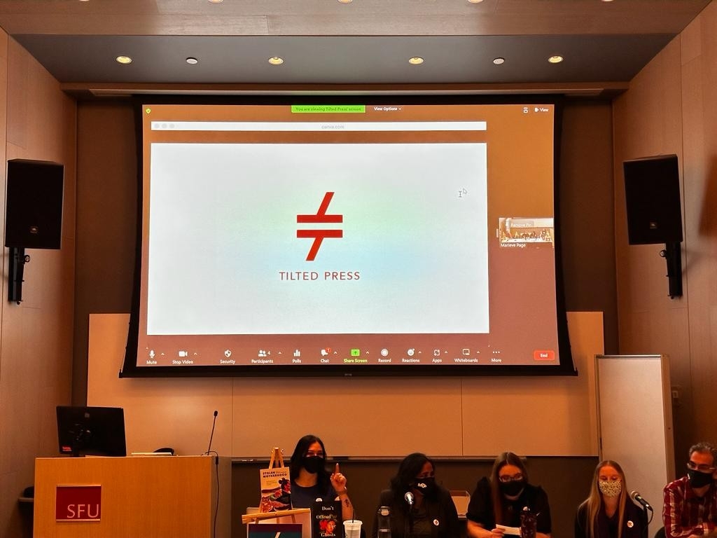 Five Master of Publishing (MPub) students presenting (behind them) the cover of their group's press catalogue: A capital T, in red, sits tilted in the middle, and exactly above it is an upside down tilted capital T, also in red. Right underneath the logo is a text that reads, Tilted Press.