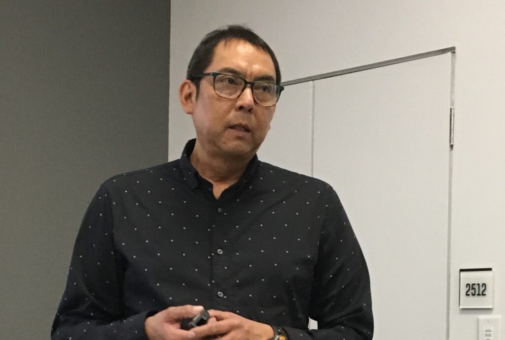 Cree man with dark hair and glasses guest lecturing at a university
