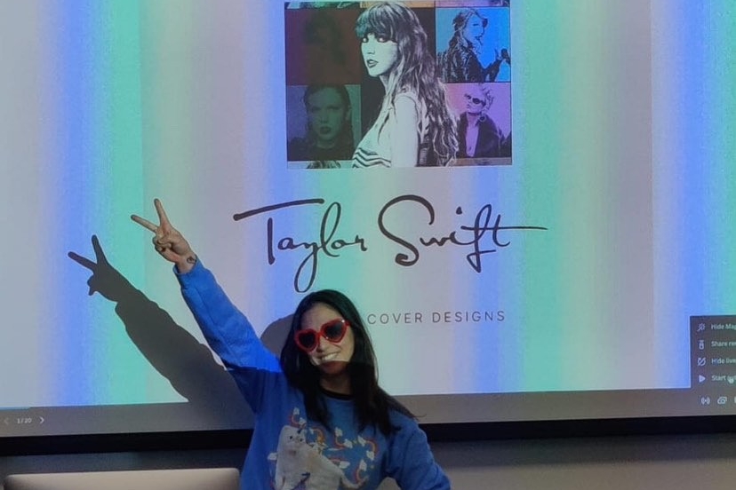 Jarin happily posing in front of a projection screen displaying a collage of Taylor Swift. Underneath the image is text which reads: Taylor Swift, Cover Designs. 