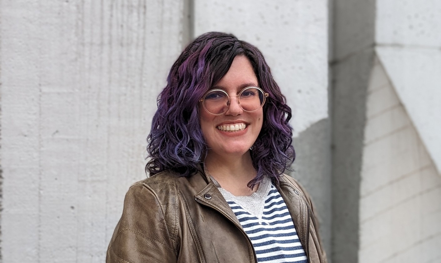A headshot of SFU Publishing lecturer Mauve Pagé with colourful hair, tinted glasses and a bright and happy smile. 