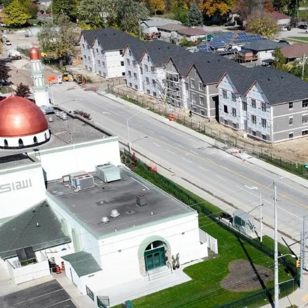 Ariel shot of a mosque with 5 buildings of multi-unit housing across the street