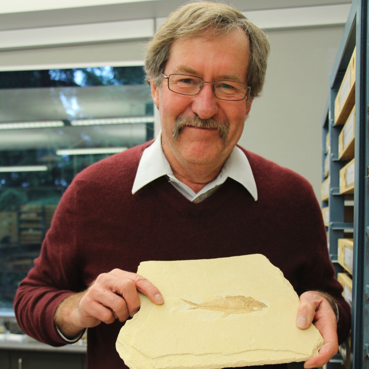 Dr. John Clague holing a fish fossil