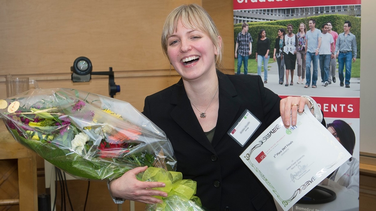 smiling graduate student holding bouquet 