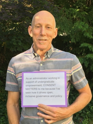 A person holding a post that says: “As an administrator working in support of undergraduate empowerment, CONSENT MATTERS to me because I've seen how it drives open, inclusive governance and policy."