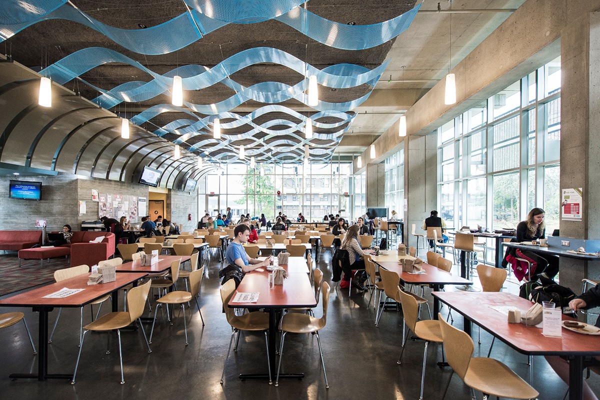 A photo of a SFU food court with multiple students eating and studying.