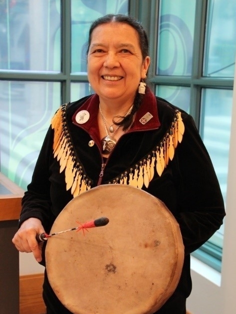 Photo of Elder Syexwaliya holding a hand drum
