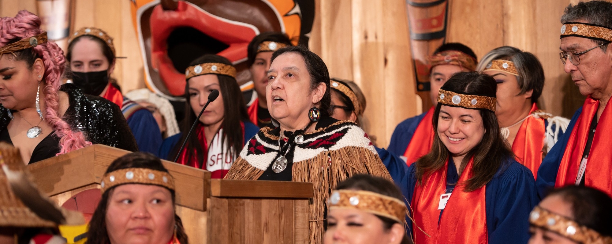 Elder Syexwaliya speaking at the Honouring Feast, surrounded by graduates