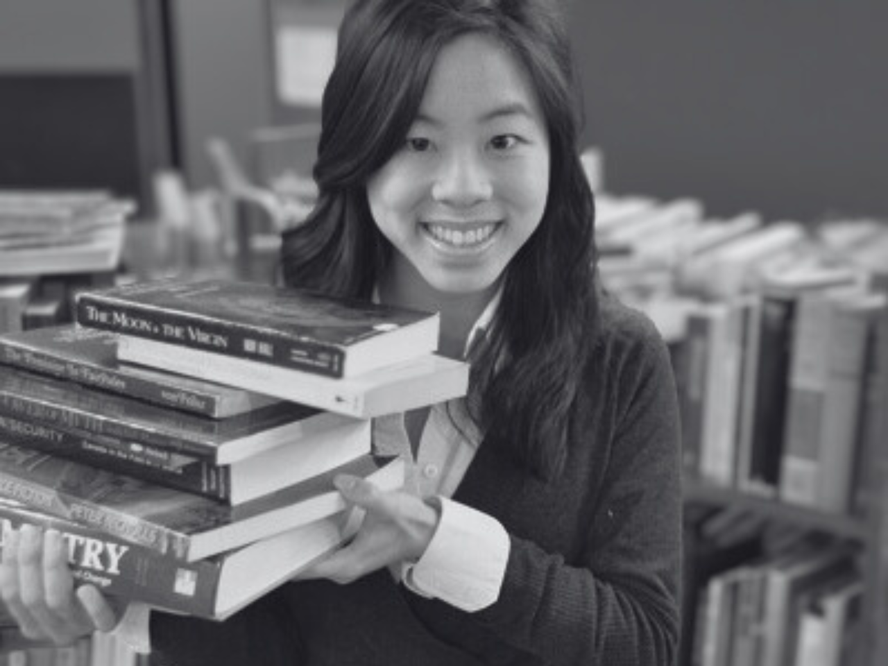 A reader poses with a stack of books.