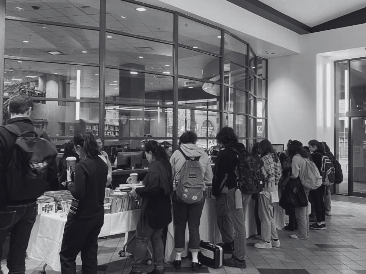 A group of students crowd a table at the Vancouver Book and Bake Sale.