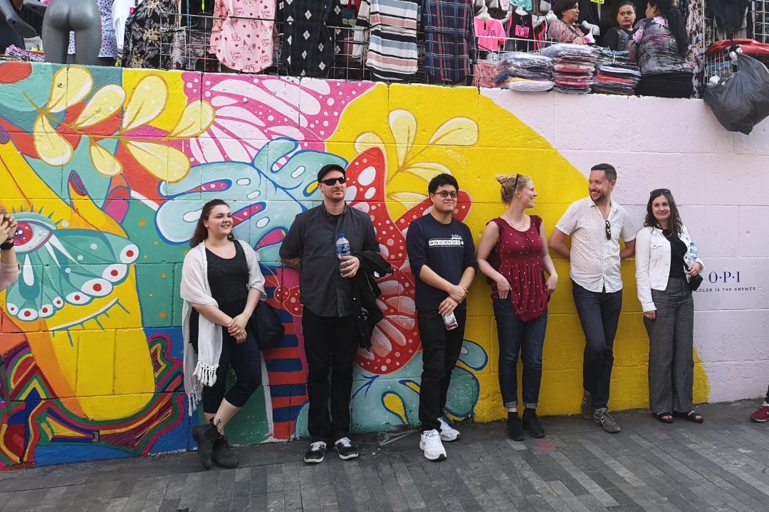 Six people standing in front of a mural on a wall; the header is Graduate Diploma in Urban Studies