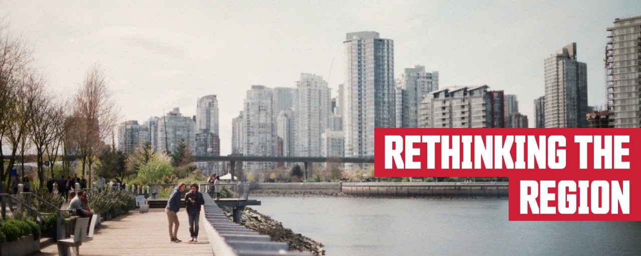 People walking along the boardwalk beside the water, skyscrapers in the background; header: Rethinking the Region
