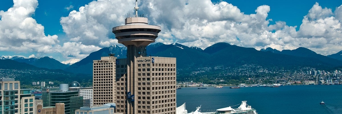 Harbour Centre tower on a bright sunny day, with the Vancouver harbour and North Shore mountains in the background