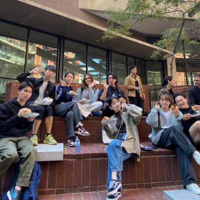 Group of students sitting and eating lunch outside of Goldcorp Centre for the Arts at a Welcome Back Community BBQ 
