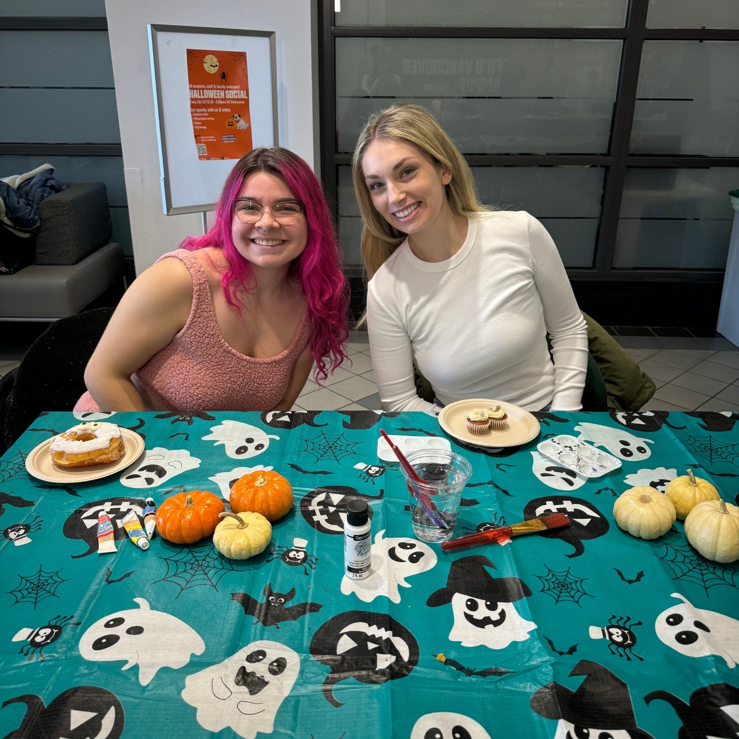 Two staff members painting pumpkins at the 2023 Halloween Social