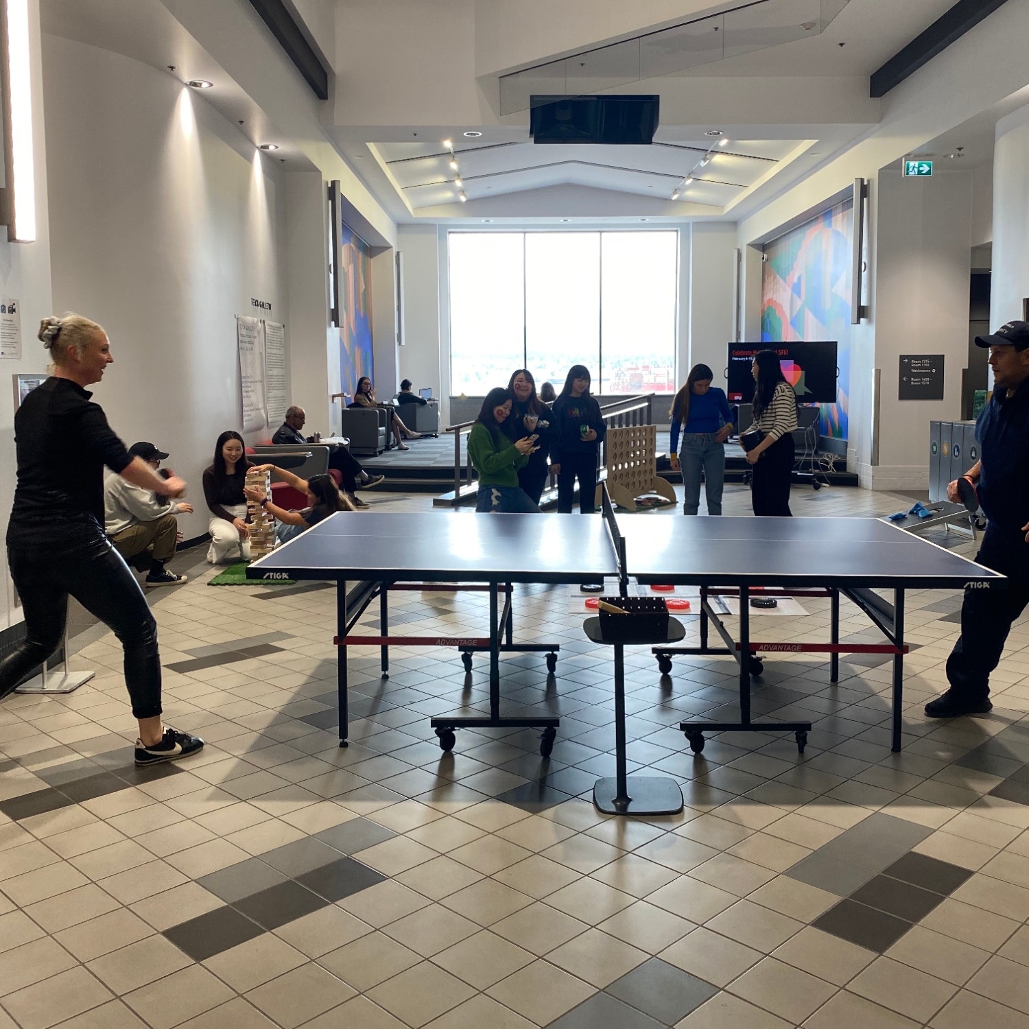 Four people playing ping pong and Giant Checkers in the Games Lounge  