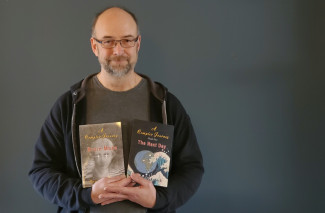Director of INN, Randy McIntosh, holds up two of his novels in this photo 