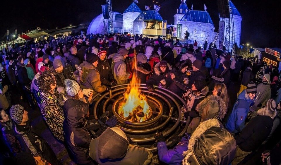 Fisheye view of carnaval attendees surrounding a campfire roasting marshmallows